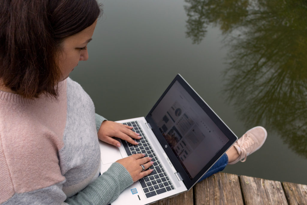 Tamara sitzt auf einem Steg und arbeitet am Laptop